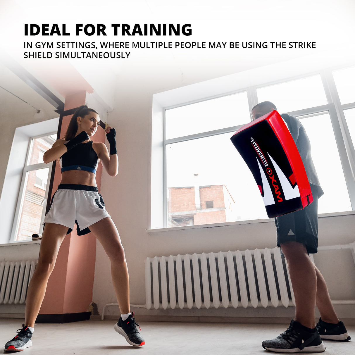 Trainer holding MAXSTRENGTH strike shield during kickboxing drill